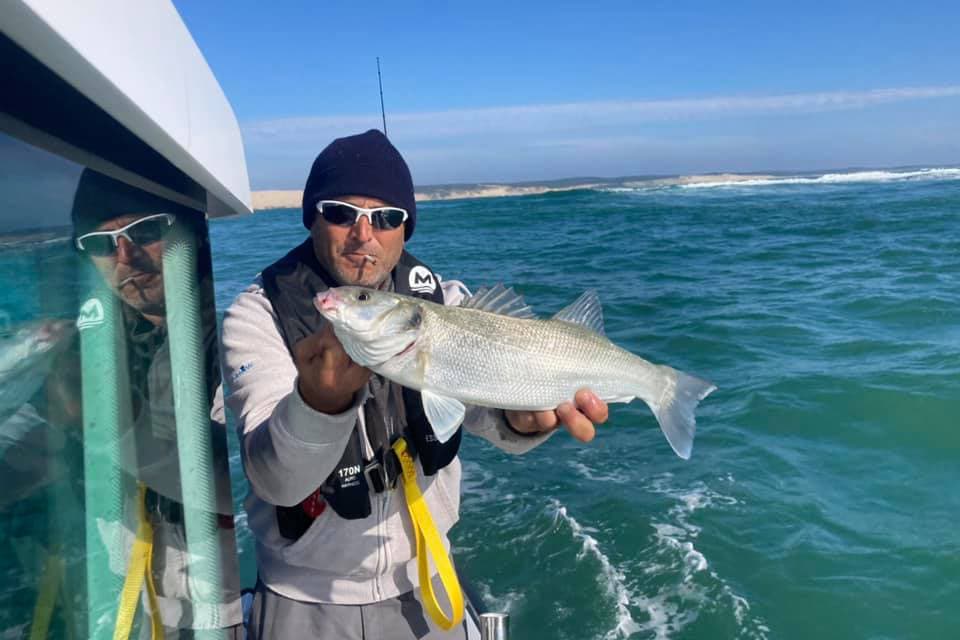 Un pêcheur tient fièrement un bar attrapé dans les passes du Bassin d'Arcachon